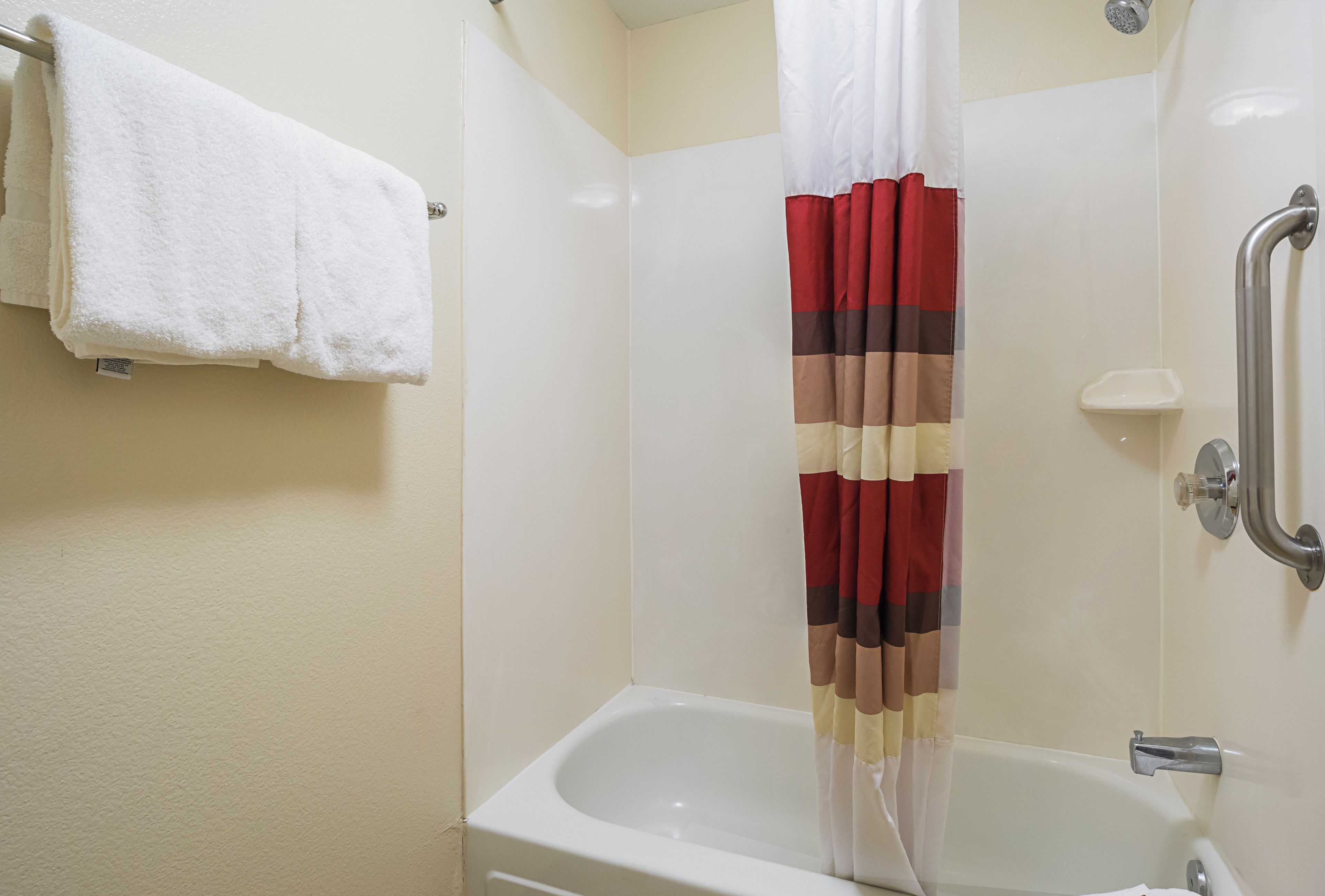 A bathroom with a white bathtub, a shower curtain with a striped pattern, and a white towel hanging on a rack.