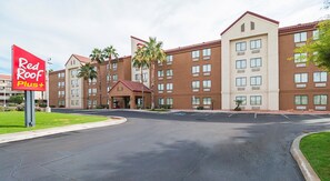 A hotel with a red and beige exterior, multiple floors, and a parking lot.
