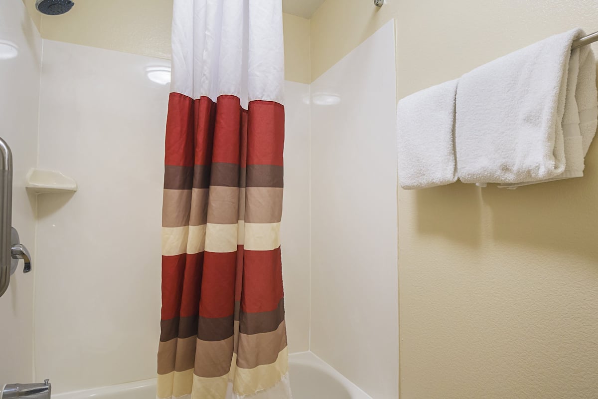 A bathroom with a shower curtain, a white bathtub, and a towel rack with two towels.