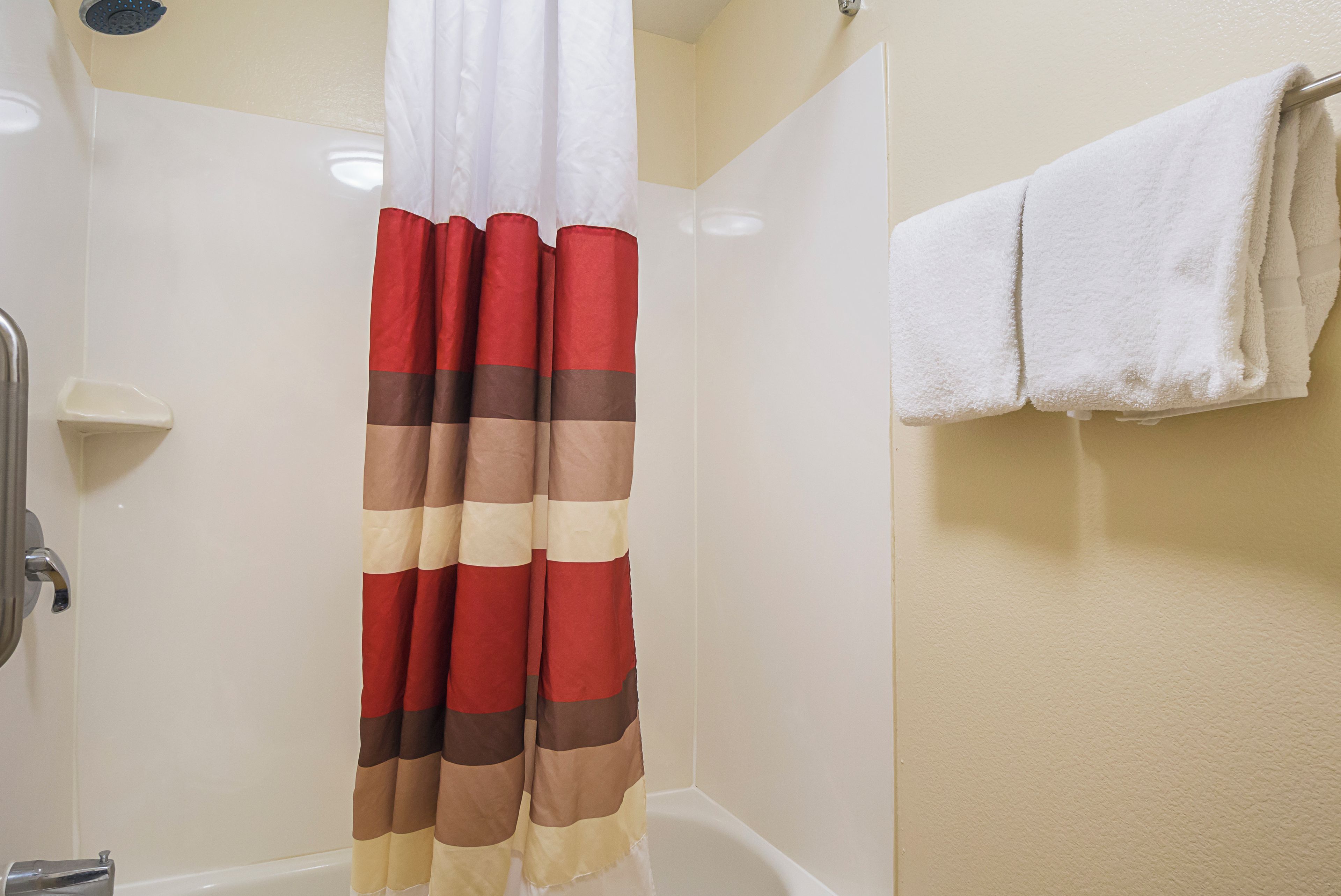 A bathroom with a shower curtain, a bathtub, and a towel rack.