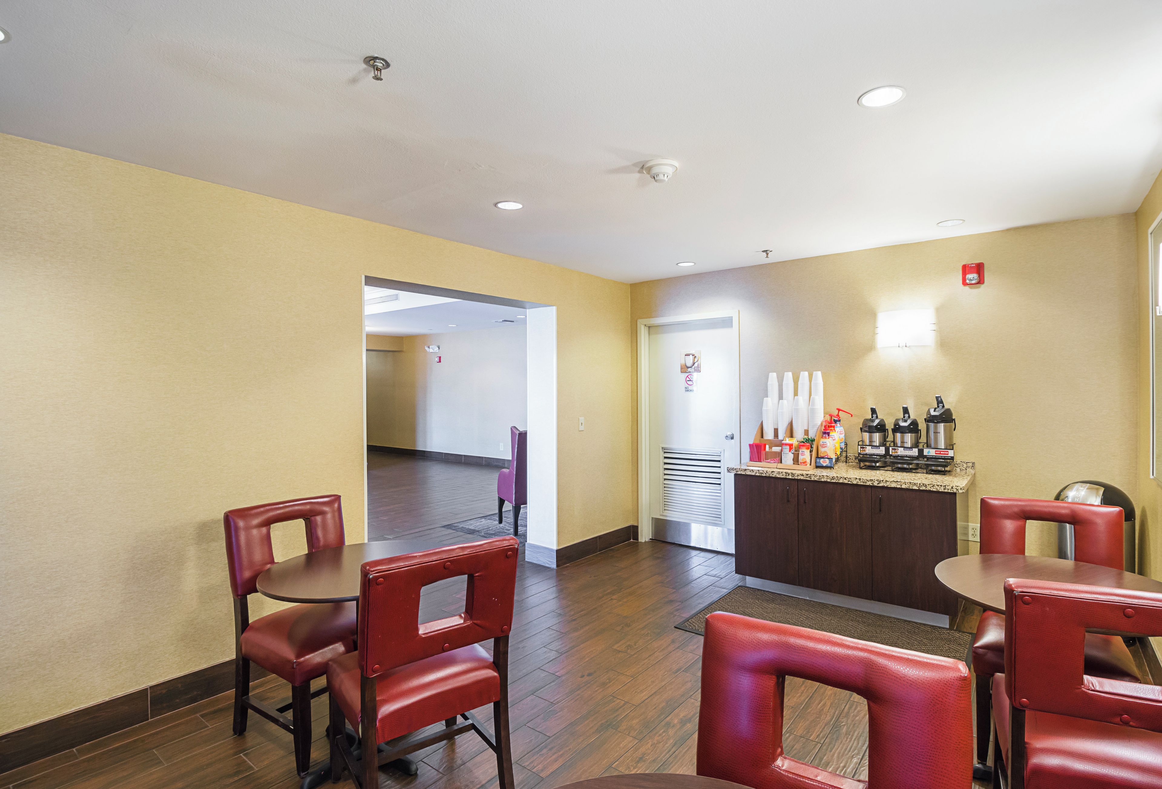 Un vestíbulo de hotel con mostrador de recepción, área de descanso y una puerta que da a otra habitación.