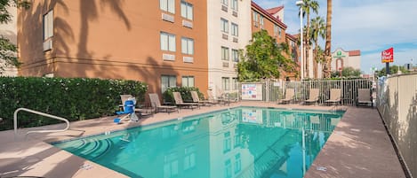 A hotel pool area with lounge chairs and a clear blue pool.