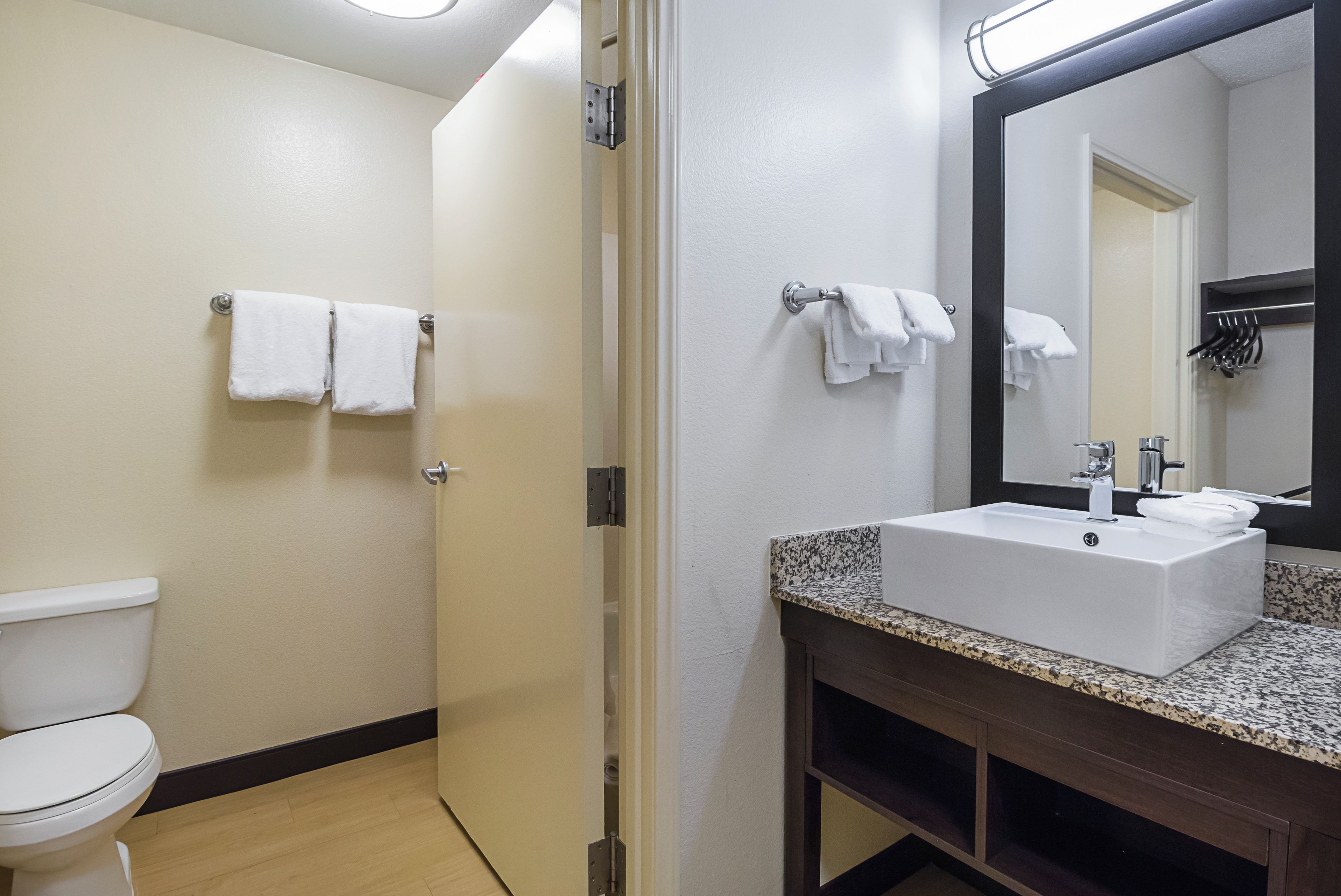 Een badkamer met een toilet, een wastafel met spiegel en twee handdoekrekken.