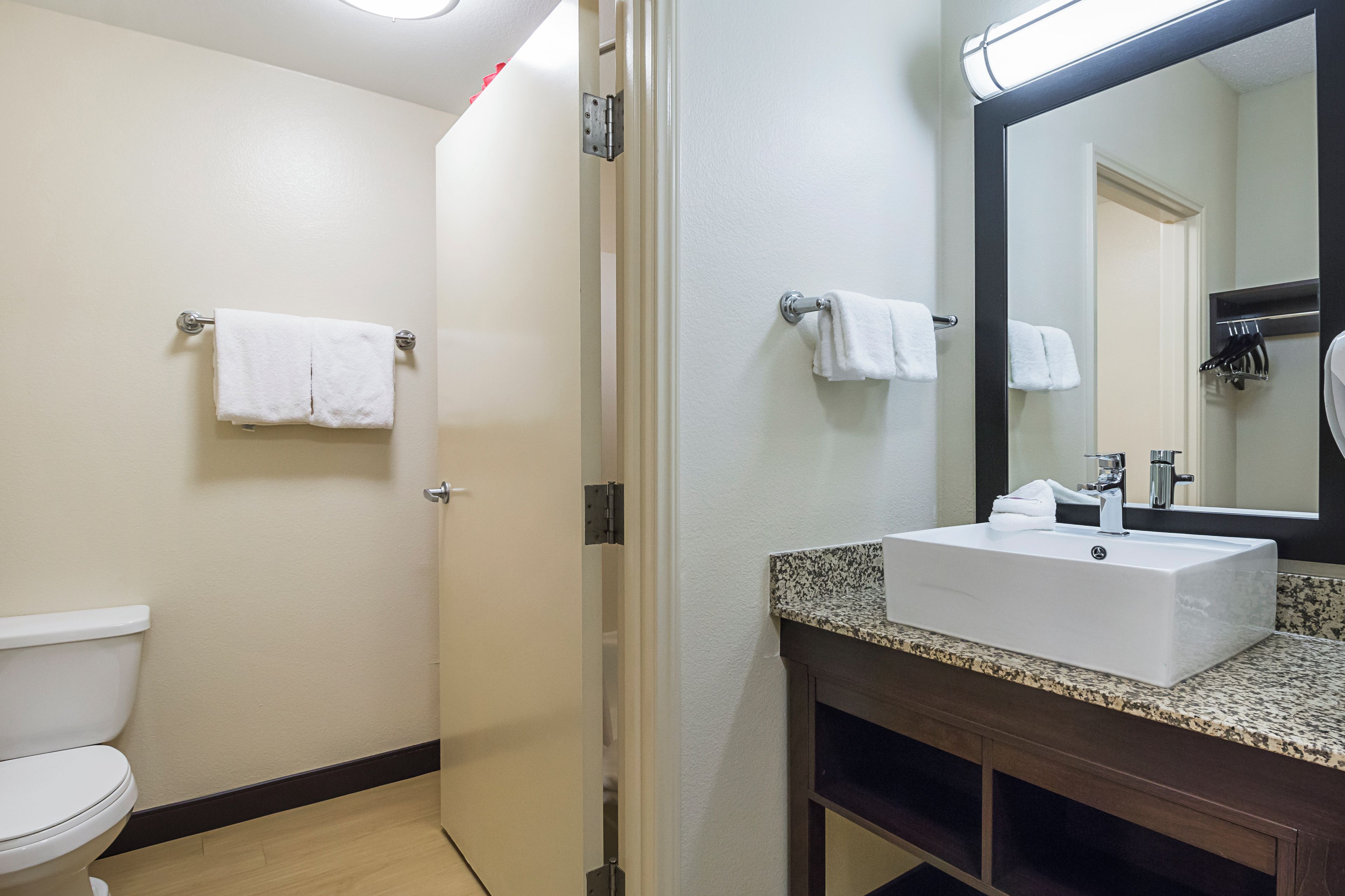 A bathroom with a toilet, a sink with a mirror, and a towel rack.