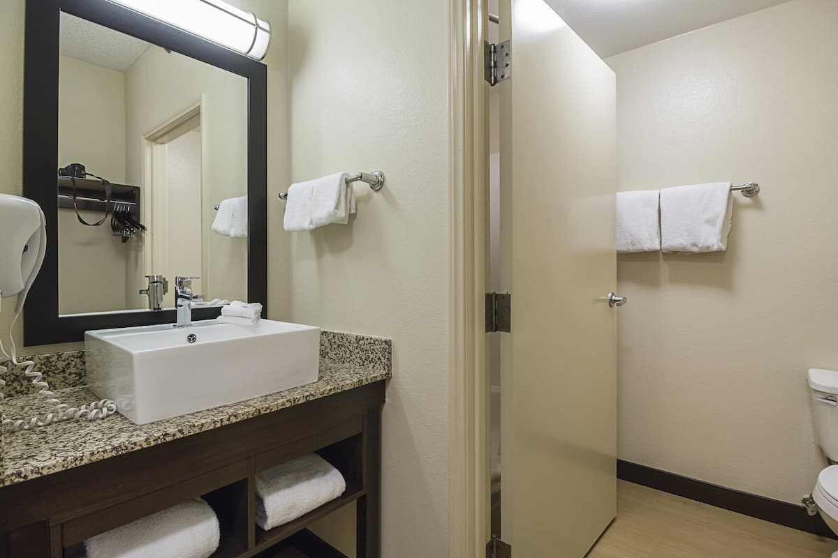 A bathroom with a sink, mirror, towel rack, and toilet.
