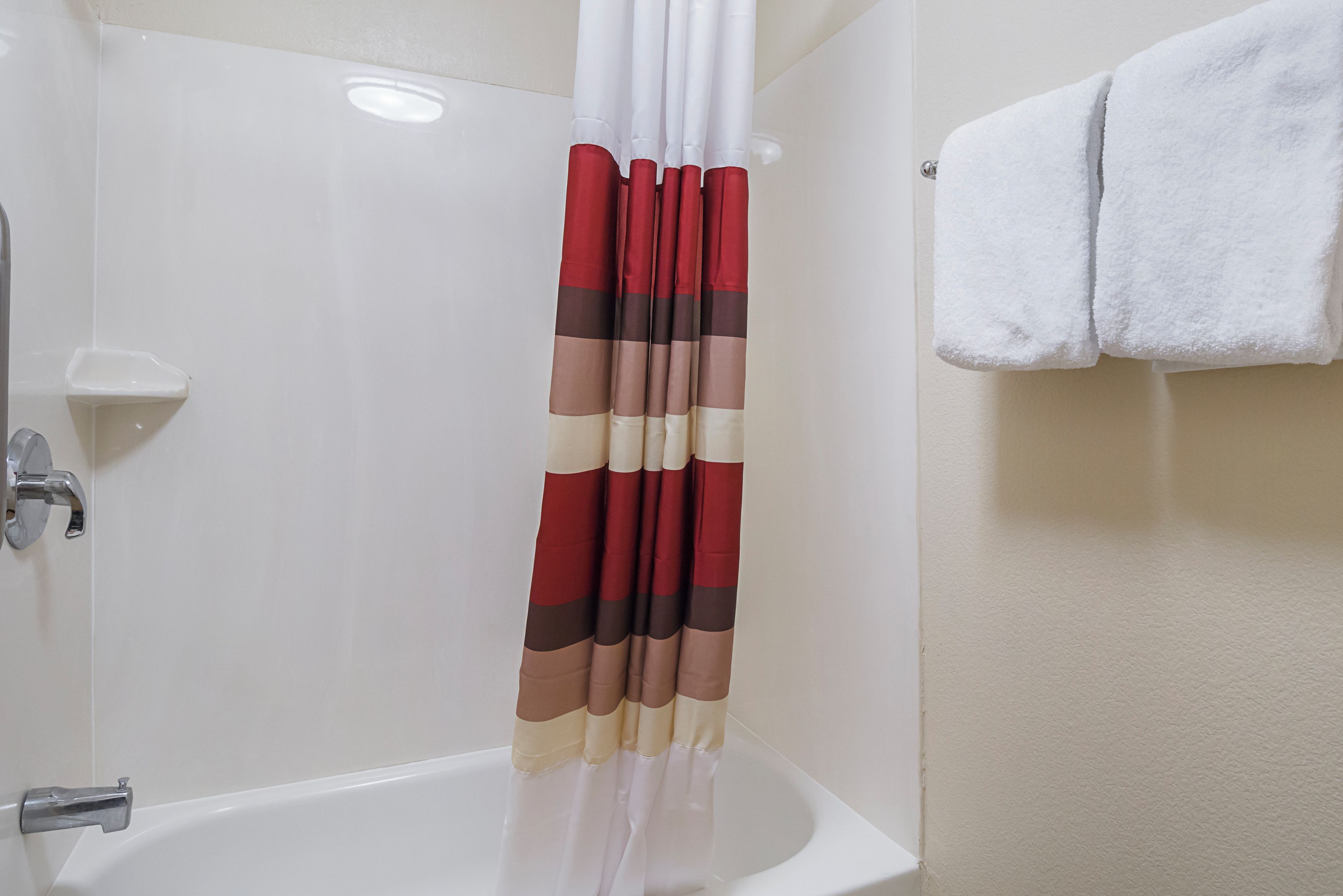 A bathroom with a bathtub, a shower curtain, and a towel rack.