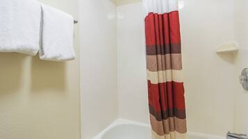 Een badkamer met een witte badkuip, een witte handdoek aan een rek en een douchegordijn in rood en beige.