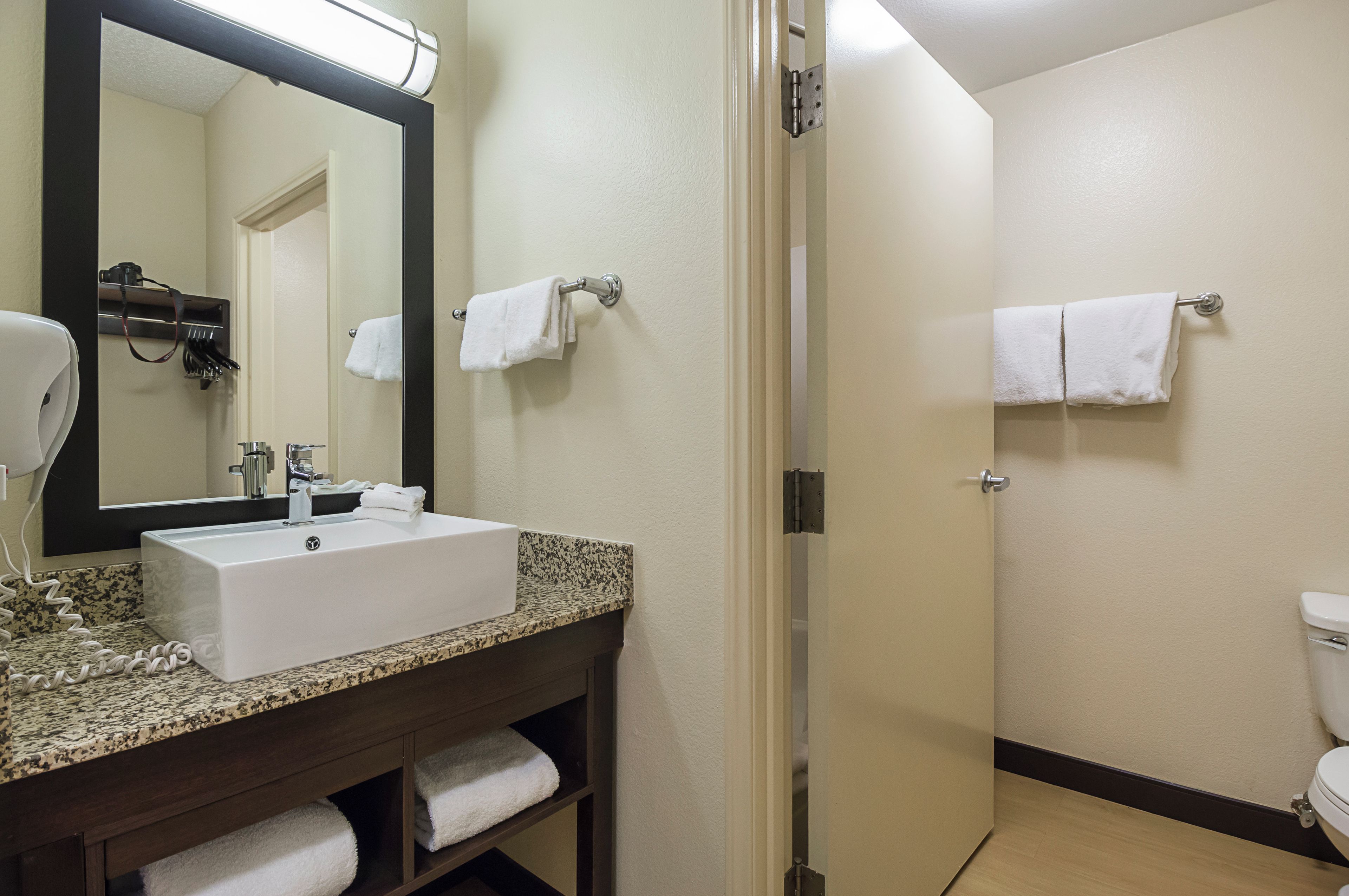 A bathroom with a sink, mirror, towel rack, and toilet.