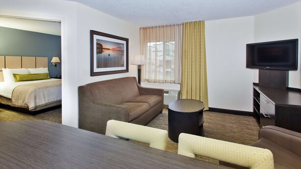 A hotel room with a bed, a sofa, a TV, and a dining table. - Sonesta Simply Suites Knoxville (Knoxville)
