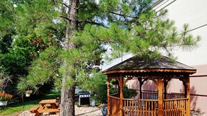 A wooden gazebo with a roof, surrounded by a gravel area and a tree. - Sonesta Simply Suites Knoxville (Knoxville)