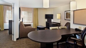 A hotel room with a bed, a seating area with a table and chairs, a television, and a lamp. - Sonesta Simply Suites Knoxville (Knoxville)