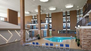Un área de piscina interior con varios niveles, sillones de descanso, una piscina y una escalera.