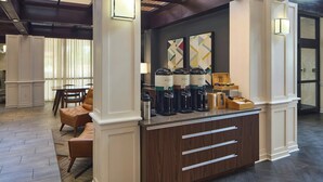 Zona de recepción con mostrador, máquinas de café y asientos.