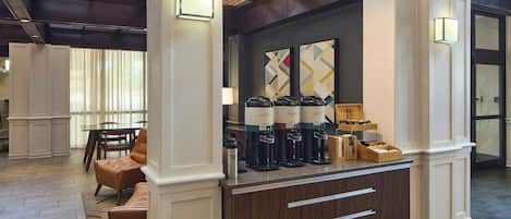 Zona de recepción con mostrador, máquinas de café y asientos.