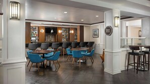 Un restaurante con barra, armarios de madera y sillas azules.