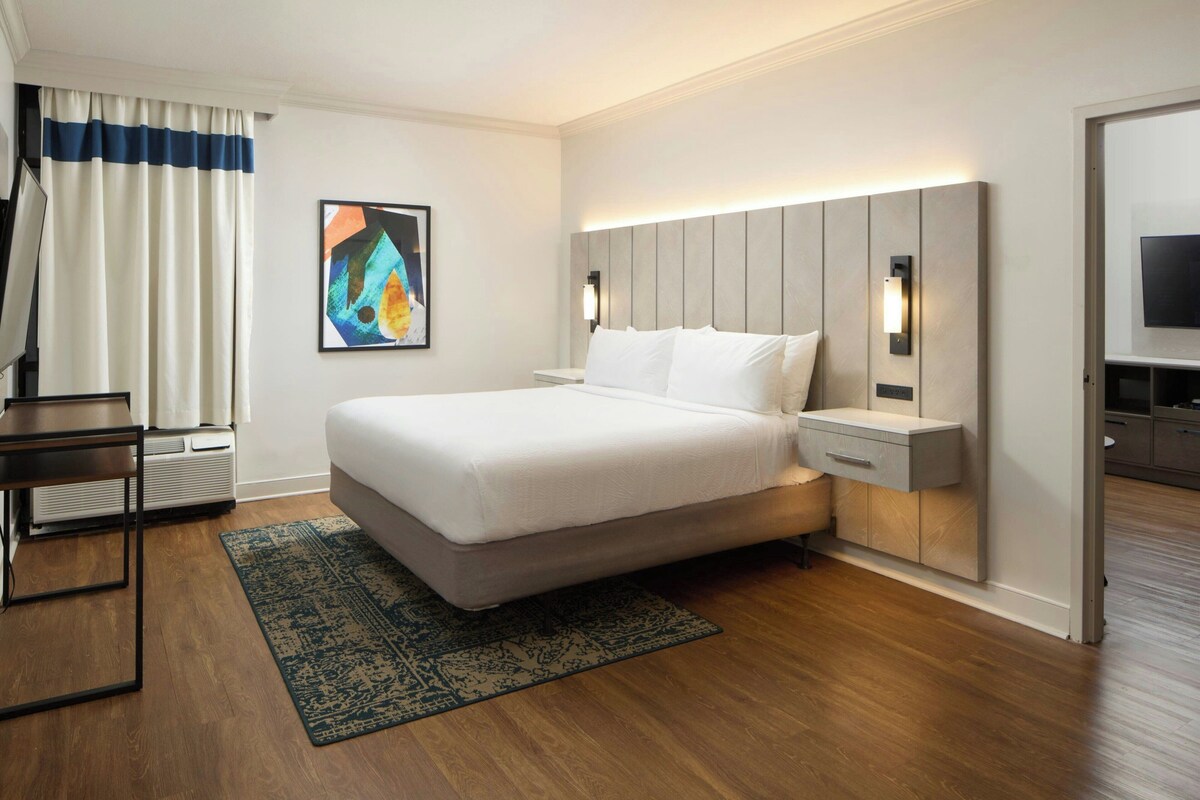 Een moderne hotelkamer met een groot bed, nachtkastjes, een bureau en een flatscreen televisie.