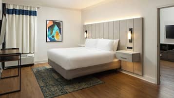 Quarto de hotel moderno com uma cama grande, mesas de cabeceira, uma escrivaninha e uma televisão de tela plana.