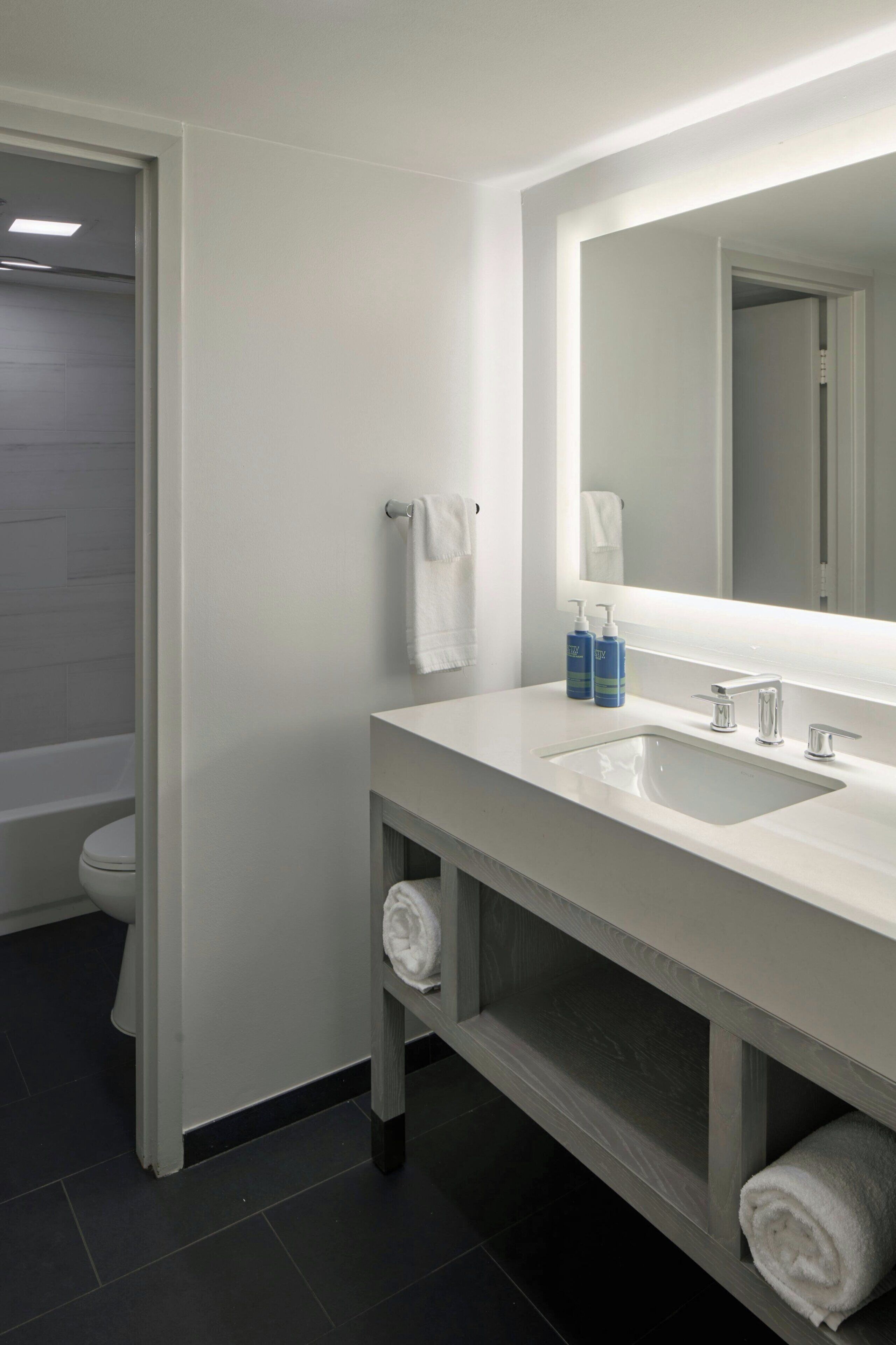 A modern bathroom with a white sink, mirror, and a shower area.
