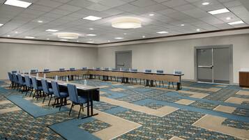 Un salón de conferencias con una larga mesa, sillas azules y una alfombra estampada.