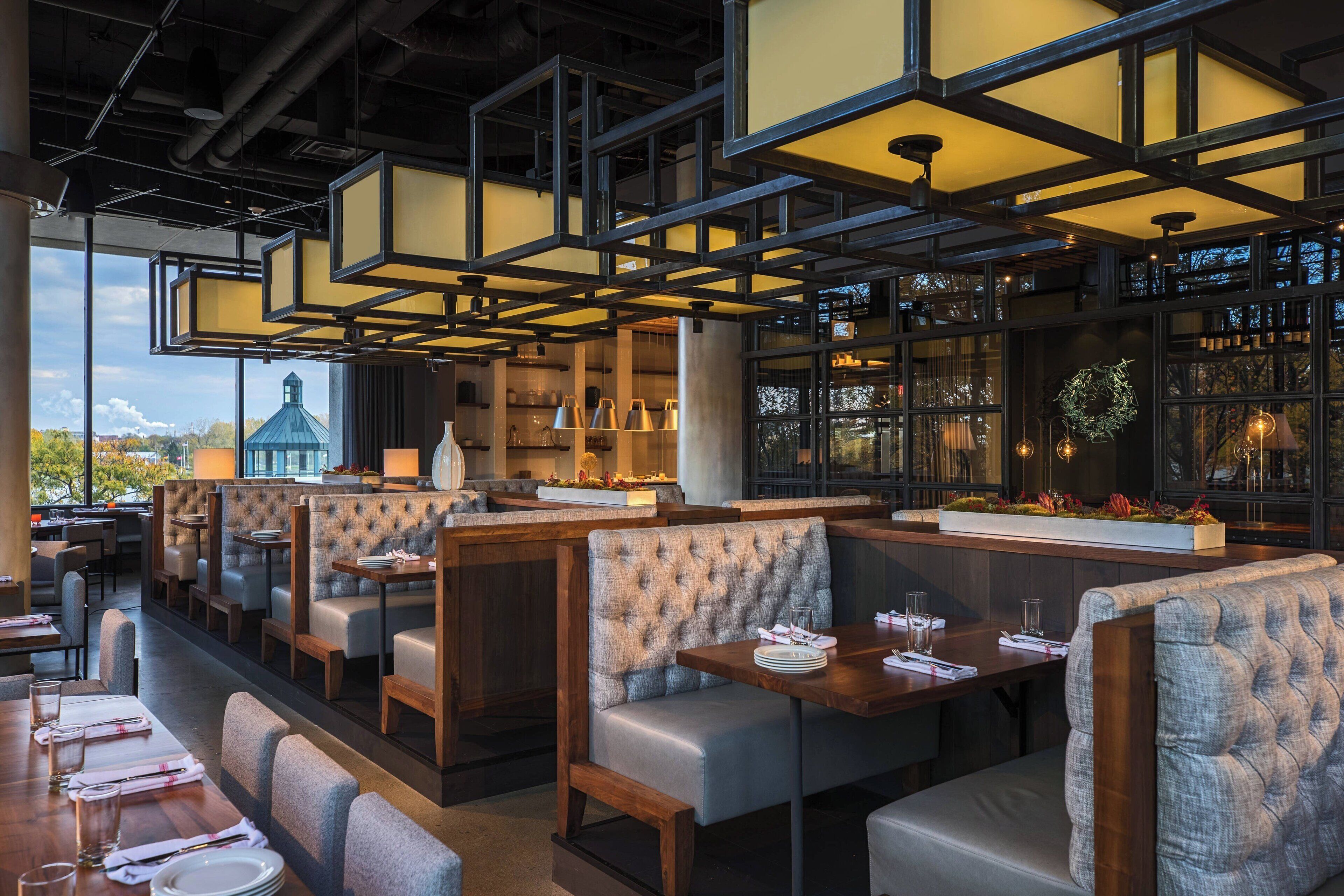 A restaurant with high-backed booths, a bar area, and a view of a building outside.