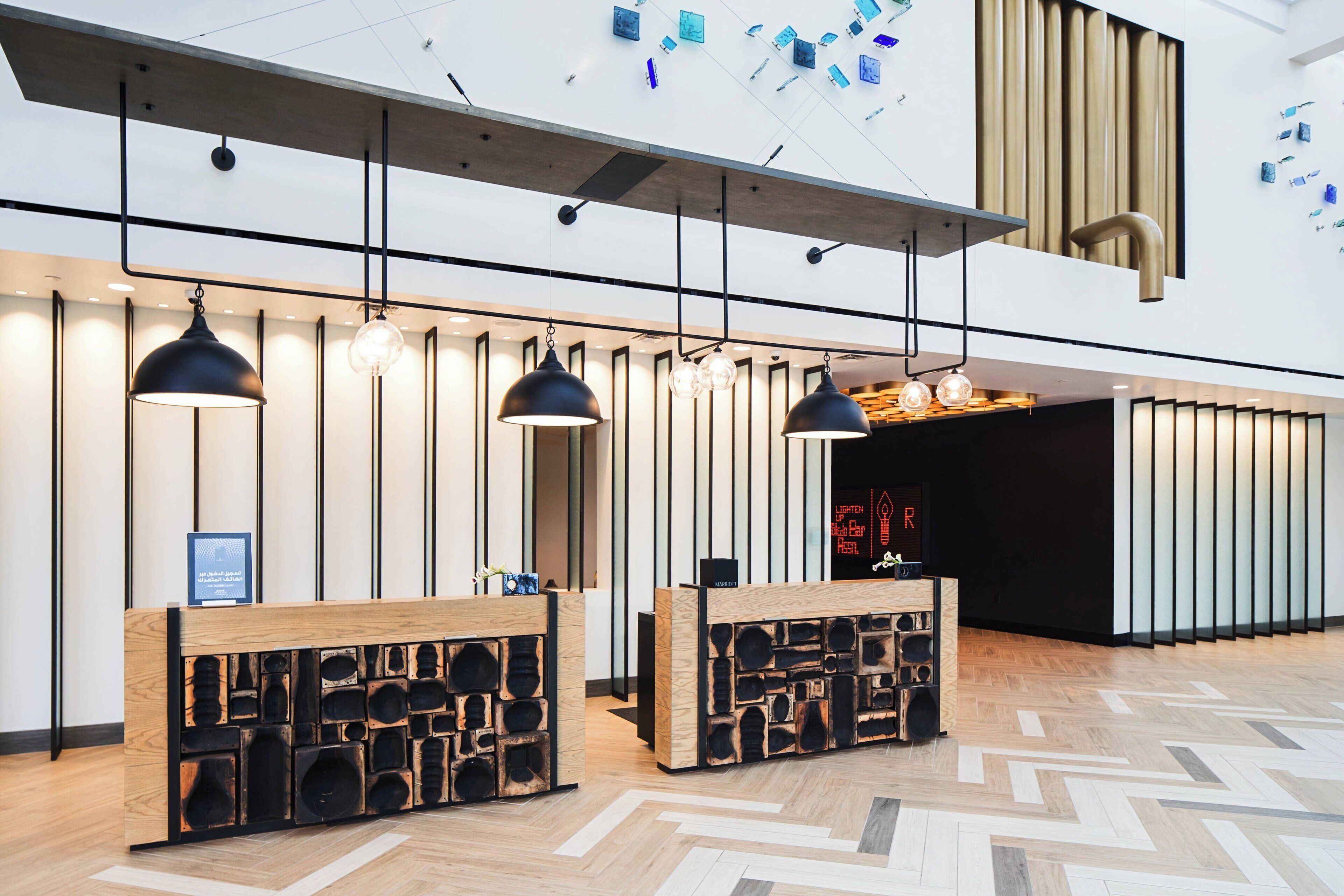 A modern reception area with wooden reception desks, pendant lighting, and a geometric patterned floor.