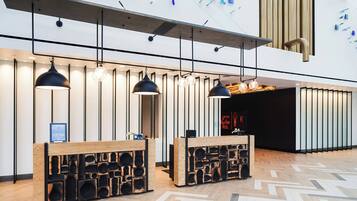 A modern reception area with wooden reception desks, pendant lighting, and a geometric patterned floor.