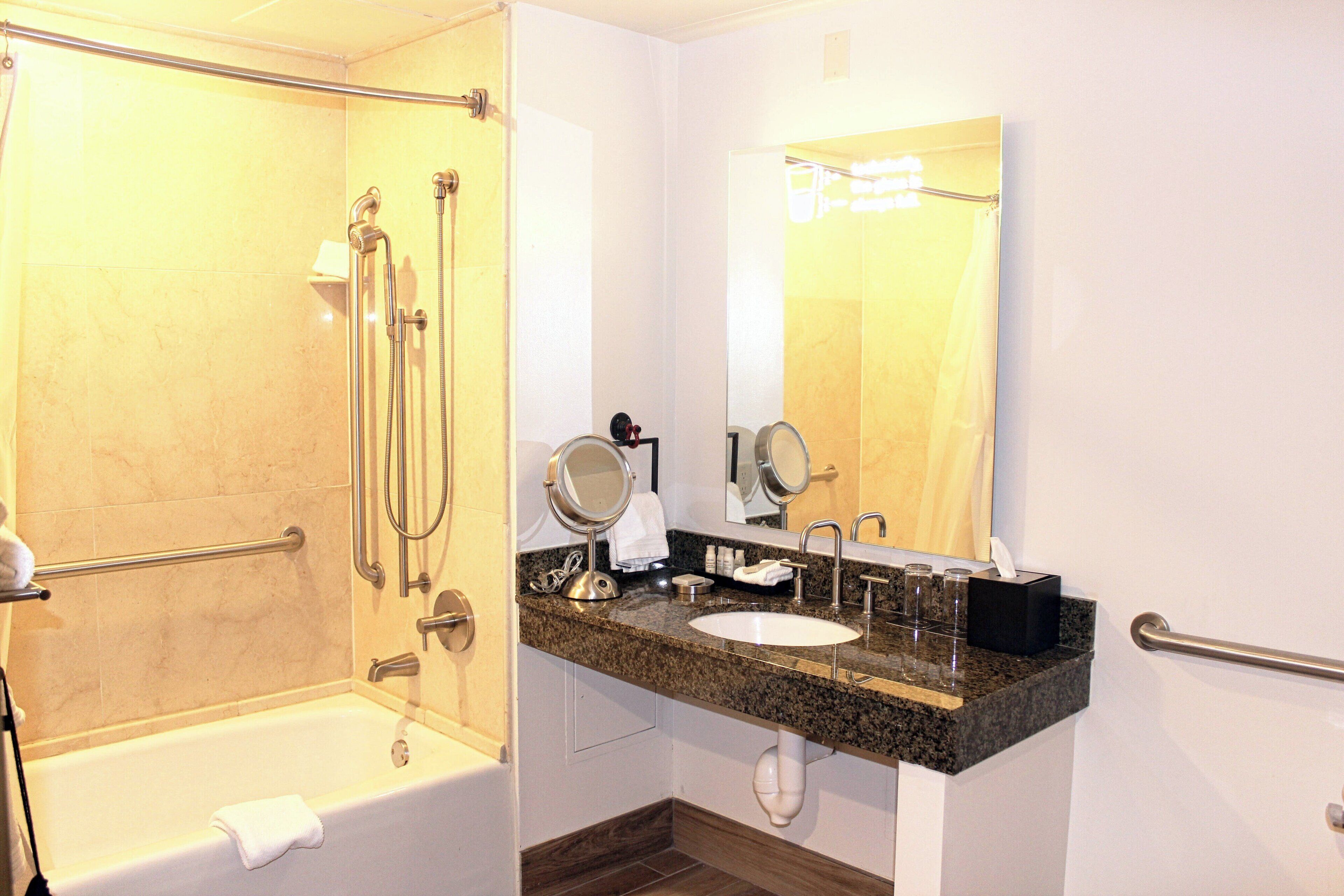 A modern bathroom with a walk-in shower, a sink with a vanity, and a large mirror.