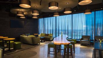 A modern lounge area with a wooden table, green ottomans, and leather chairs.