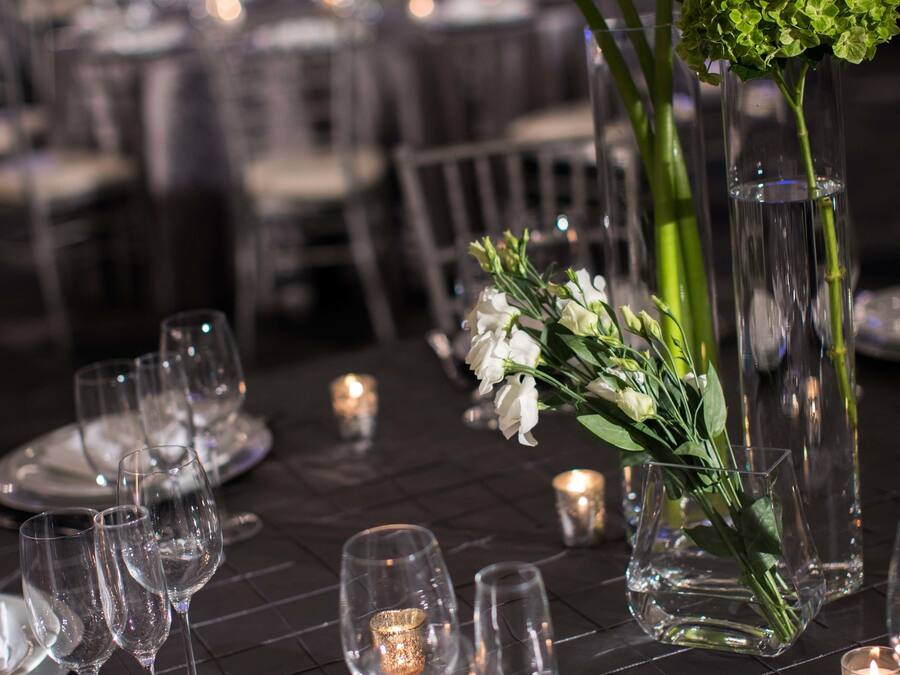 A table set for a formal event with clear glassware, white plates, and floral centerpieces.