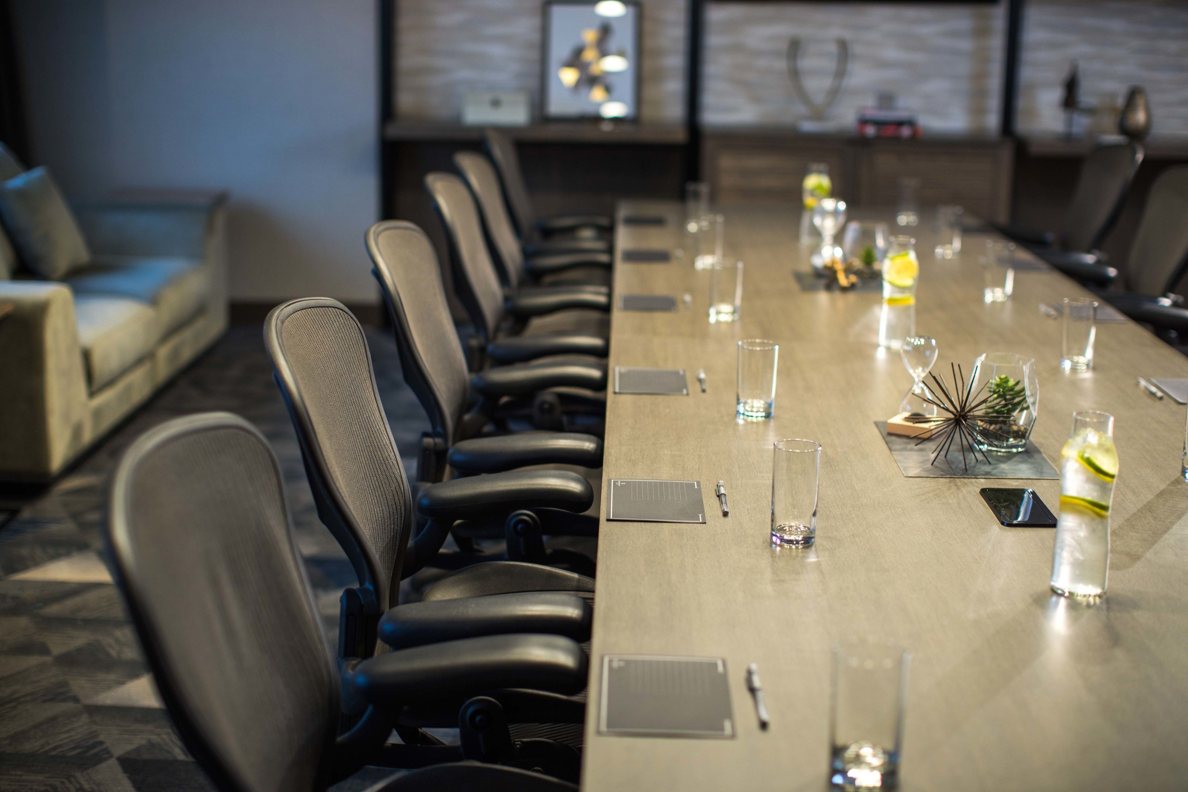 Une salle de conférence avec une longue table, des chaises et un canapé.