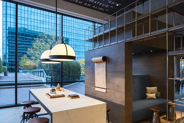 A modern interior with a large window, a central island with stools, a sofa, and a hanging light fixture.