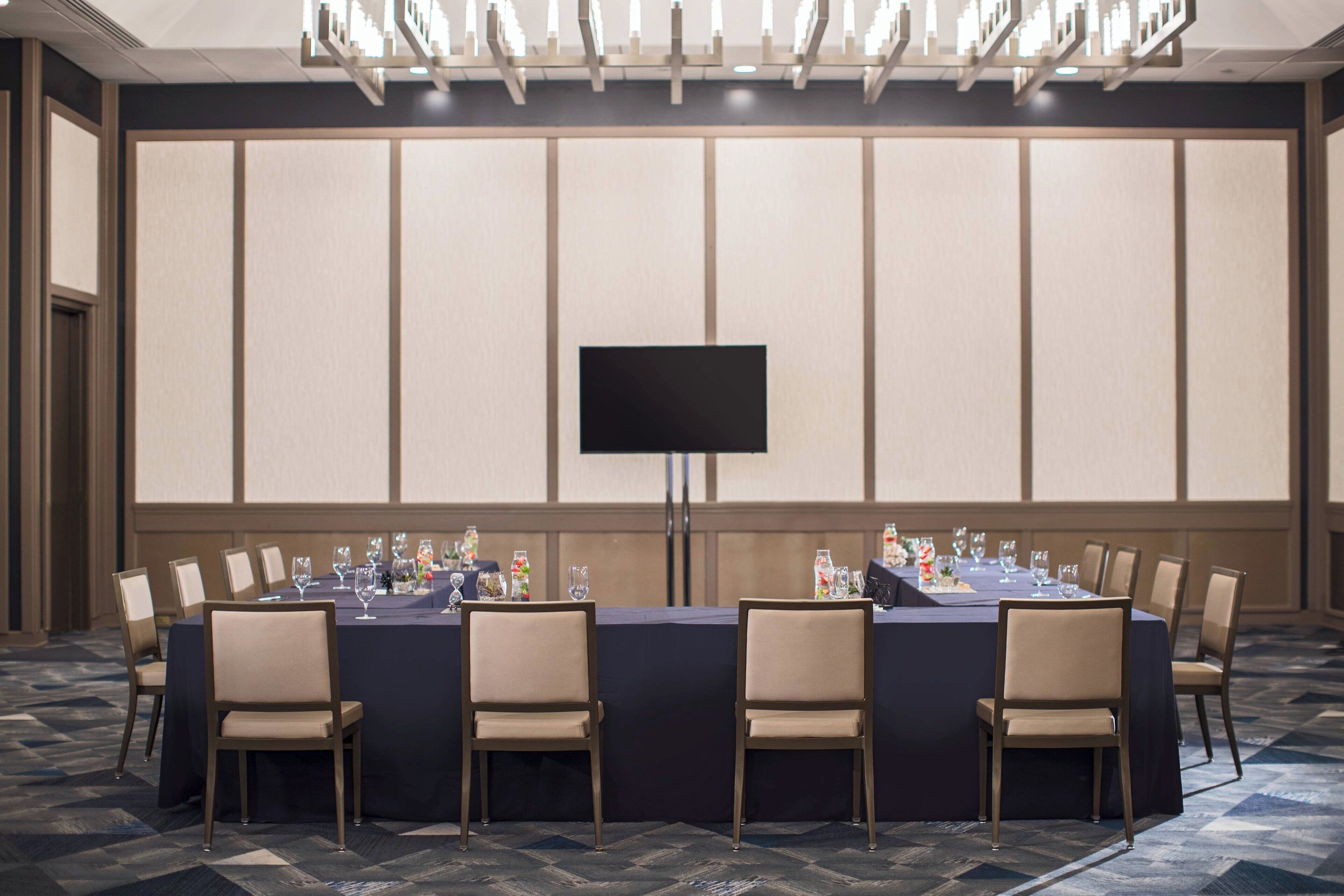 A conference room with a long table, chairs, and a flat-screen TV.