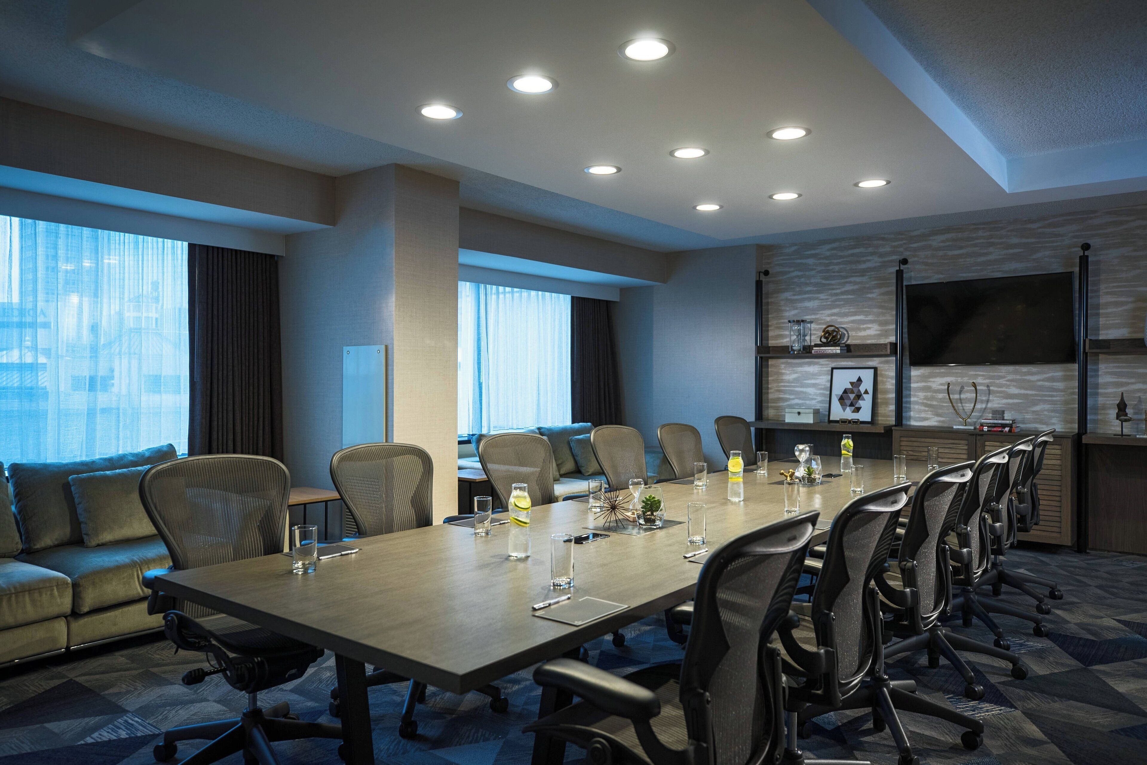 A conference room with a long table, multiple chairs, and a sofa.