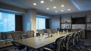 Une salle de conférence avec une longue table, de nombreuses chaises et un canapé.