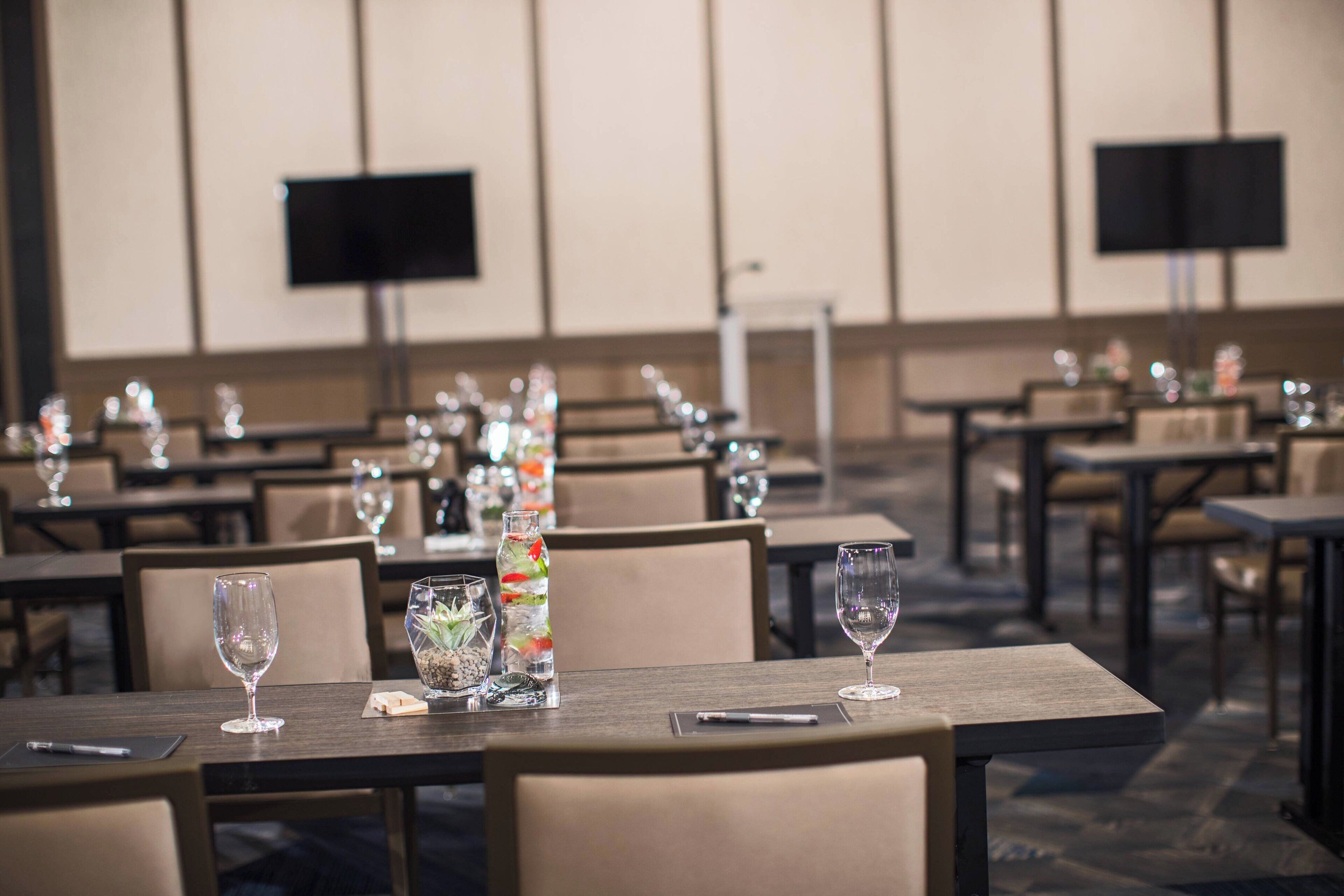 Une salle à manger d’hôtel avec plusieurs tables, chacune agrémentée de verres à vin et de bouteilles d’eau.
