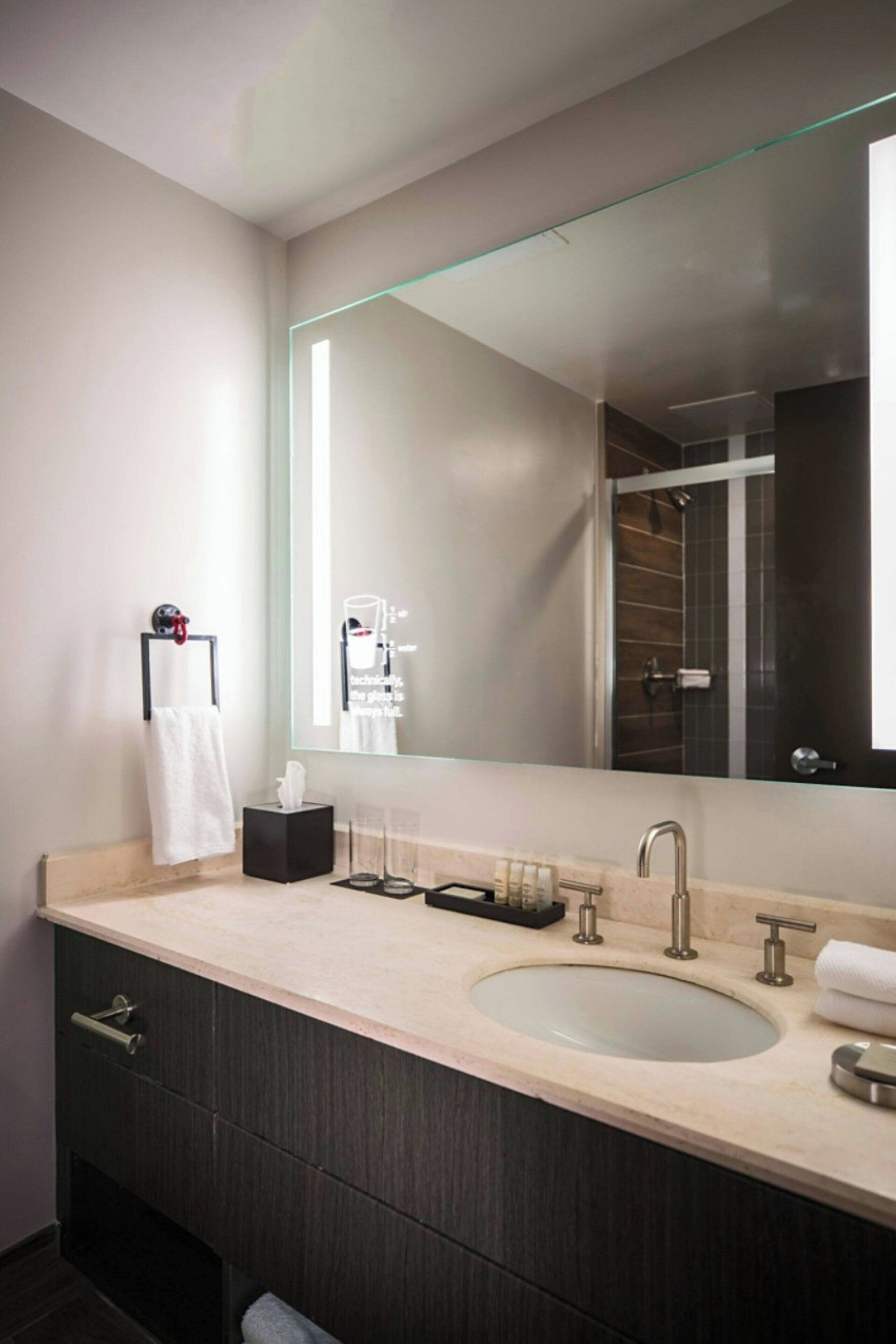 Un baño moderno con un espejo grande, un lavabo y un perchero para toallas.