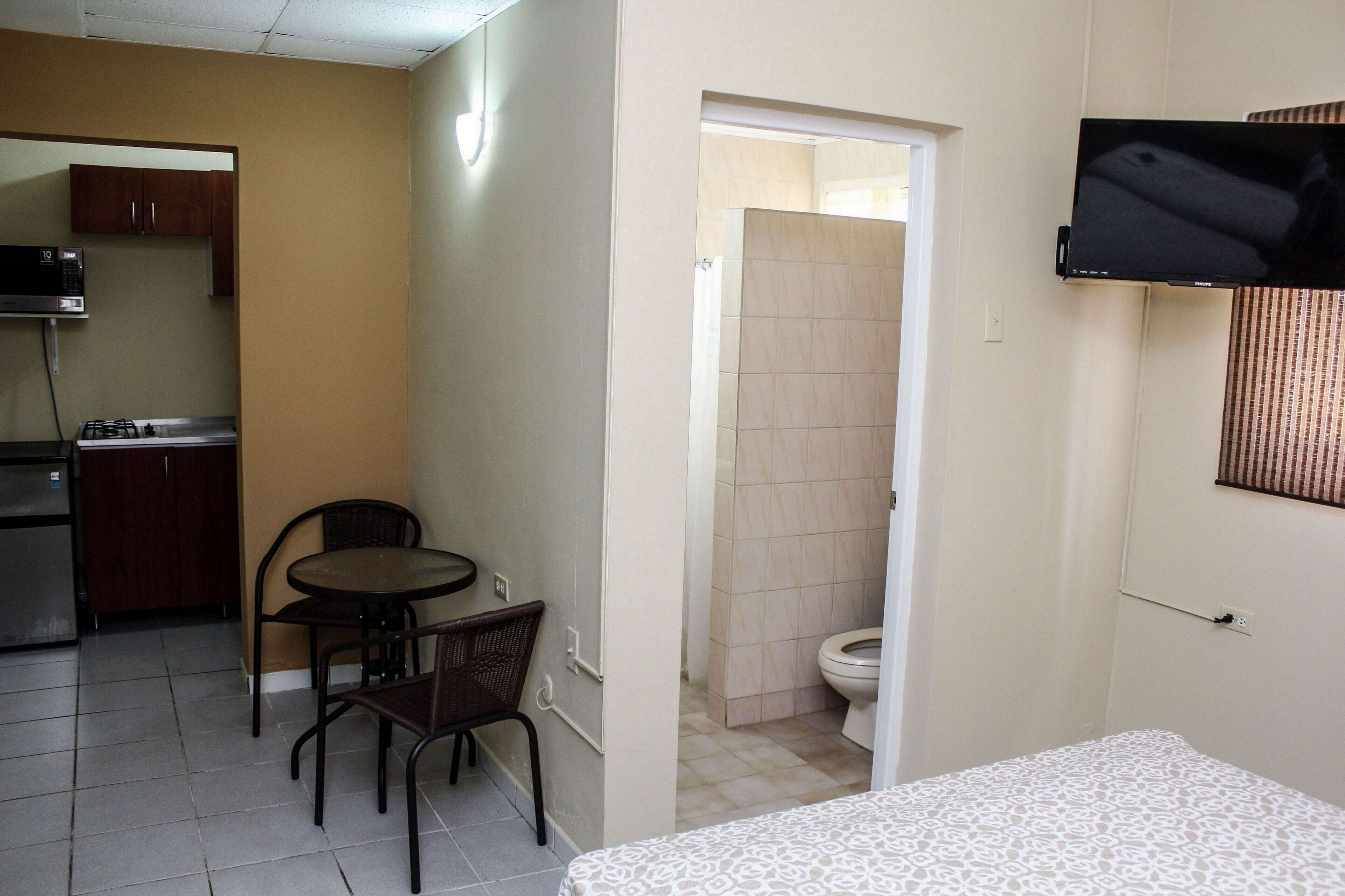 A compact hotel room with a kitchenette, a dining area, and a bathroom.