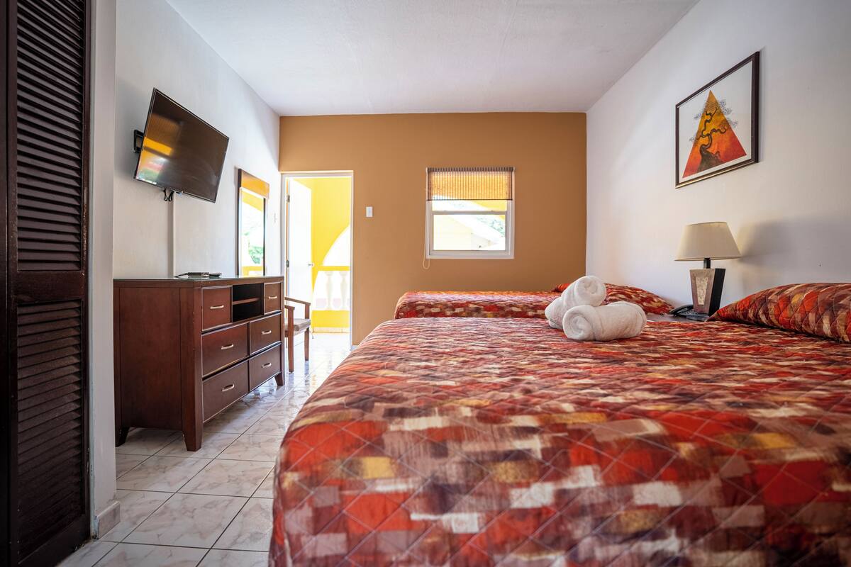 A hotel room with a bed, a TV, a desk, and a window.