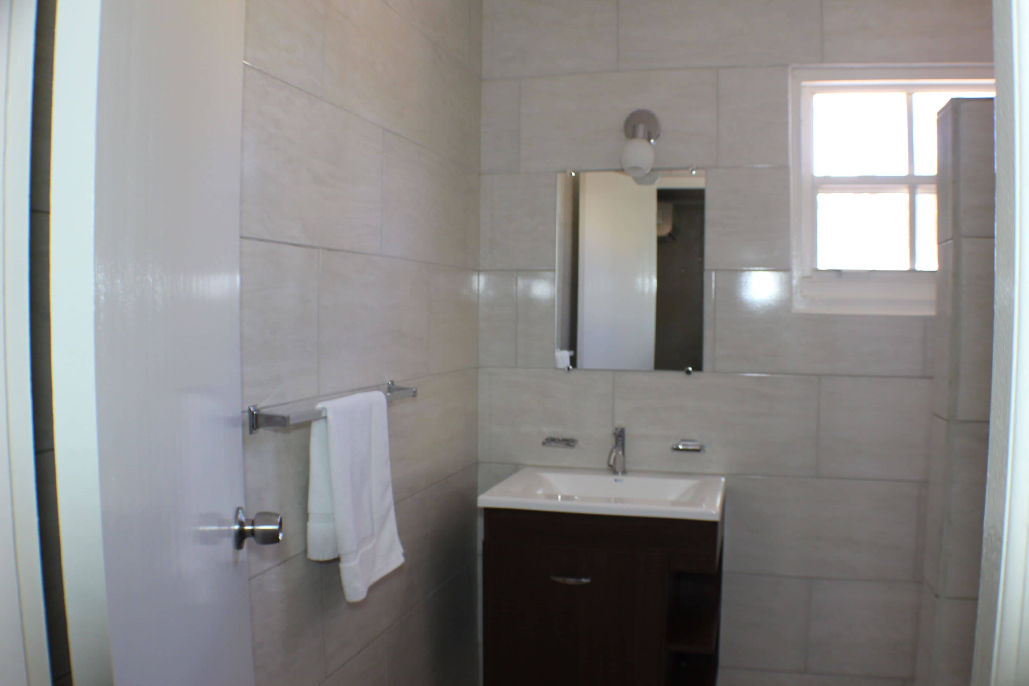 A bathroom with a white sink, a mirror, and a towel hanging on a rack.
