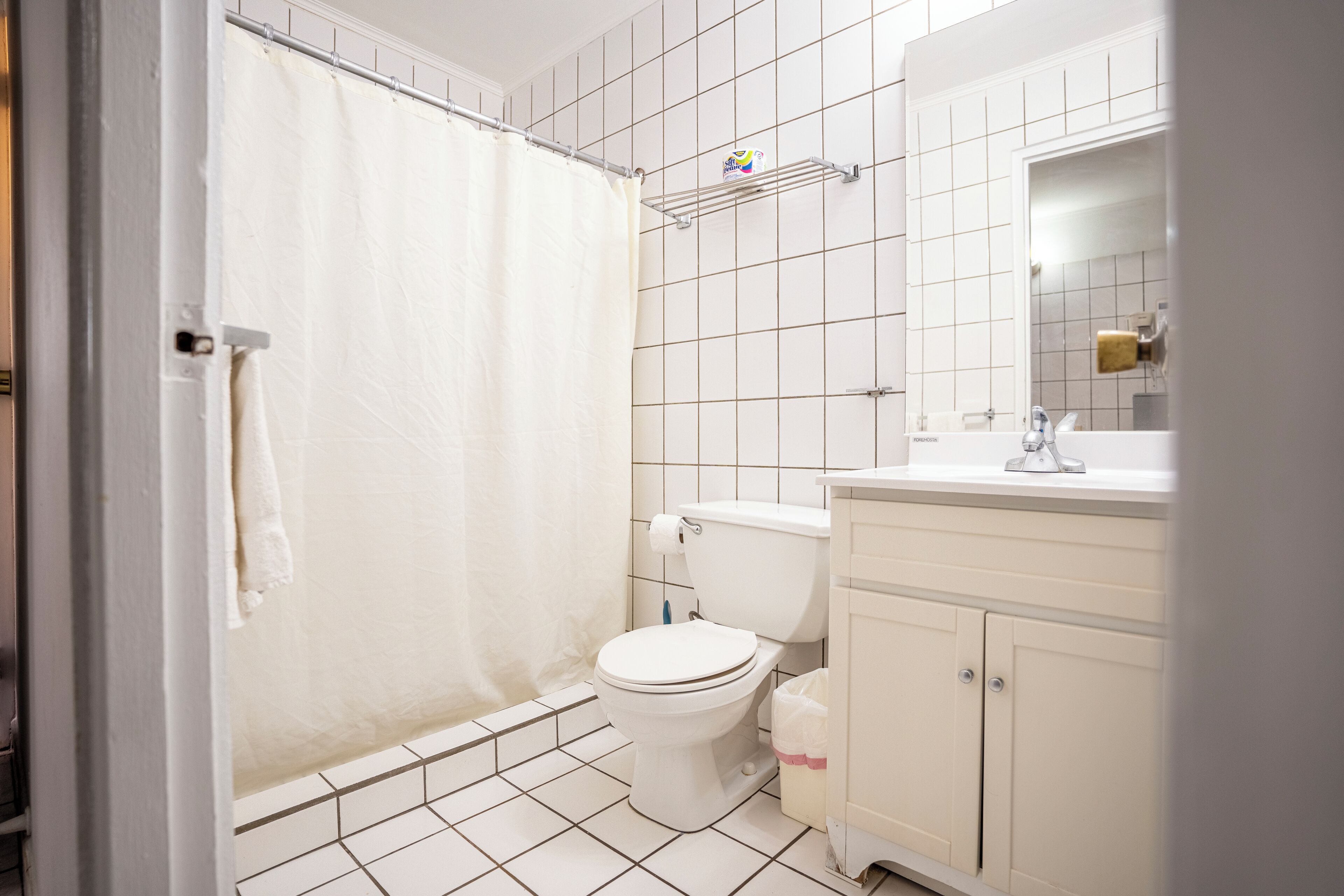 Un baño con inodoro, lavamanos, espejo y cortina de ducha.