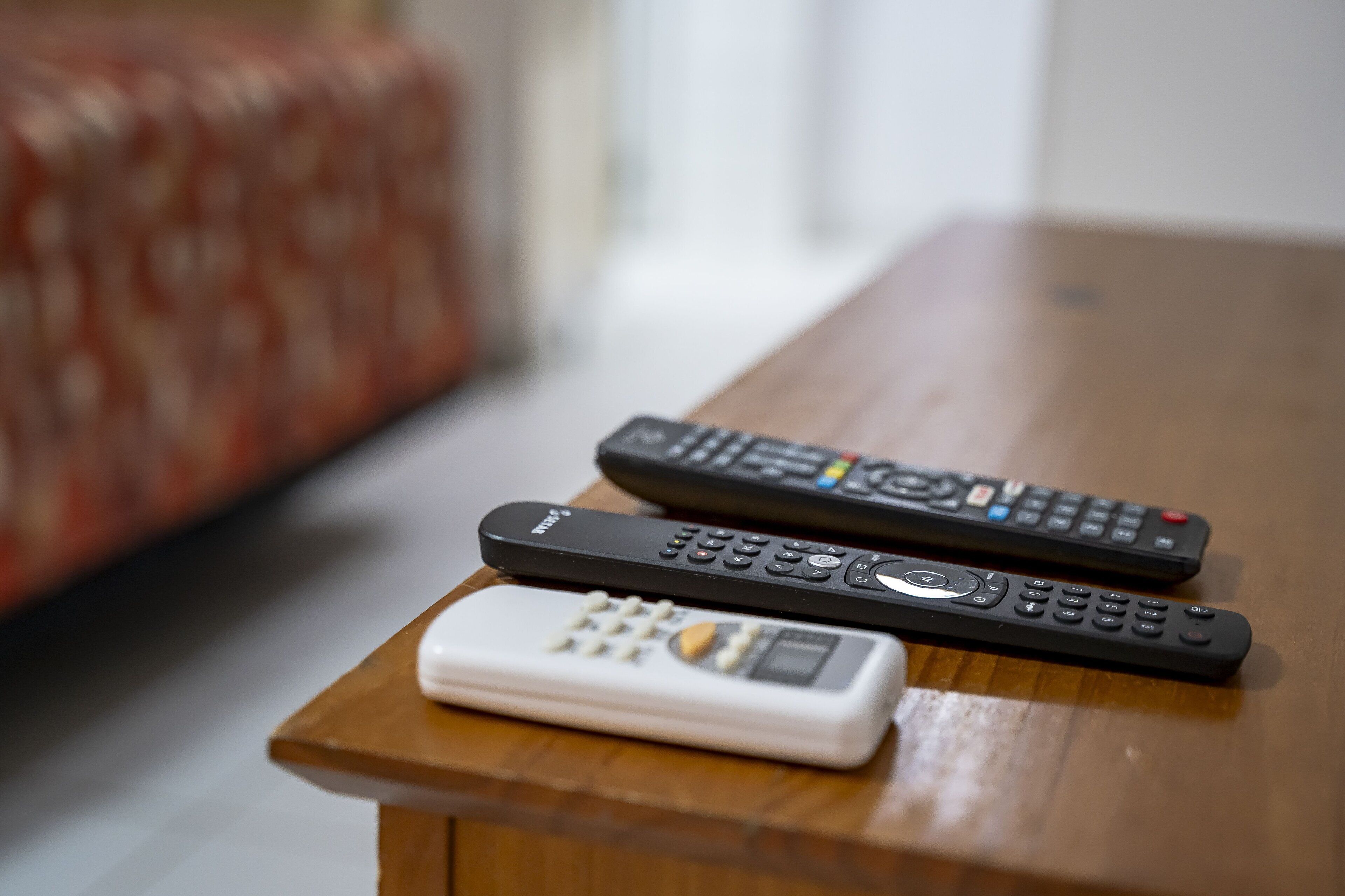 Two remote controls and a small device on a wooden table.
