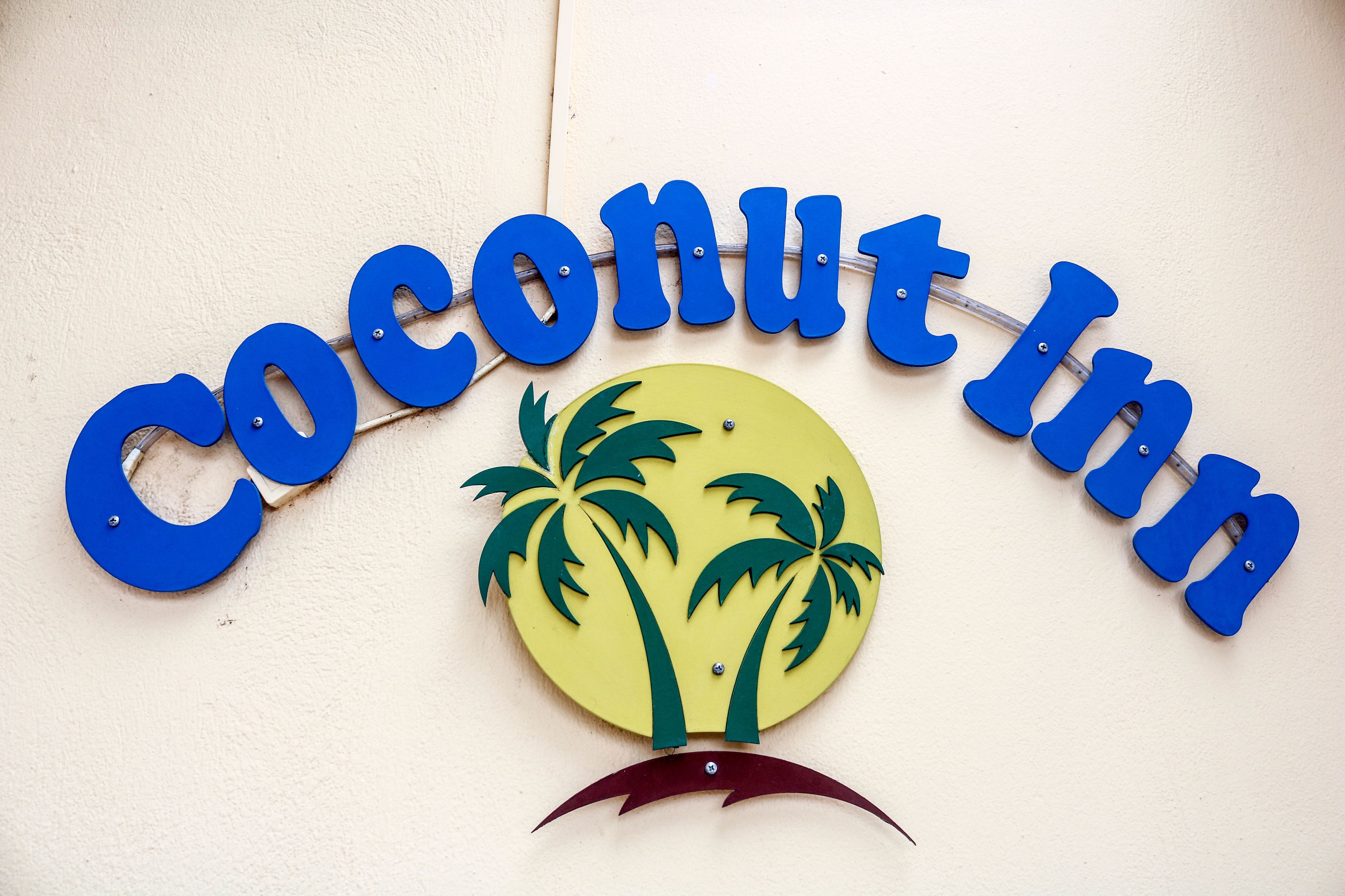 Un senyal amb la paraula 'Coconut Inn' i un dibuix d'una palmera.