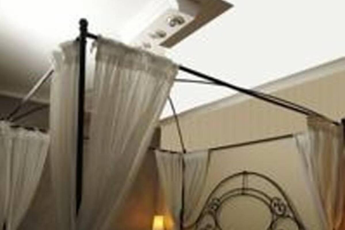 A four-poster canopy bed with a headboard, a bedside table, and a lamp.