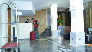 A lobby with a reception desk, a staircase, and a luggage cart. - Reina Victoria Suites & Towers (Mendoza)