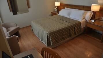 Une chambre d’hôtel comprenant un lit, deux tables de chevet, un bureau avec une chaise et un ordinateur portable.