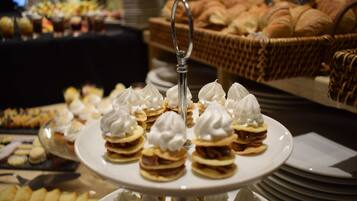 Una mesa con varios platos de postres en capas y una cesta de pan al fondo.