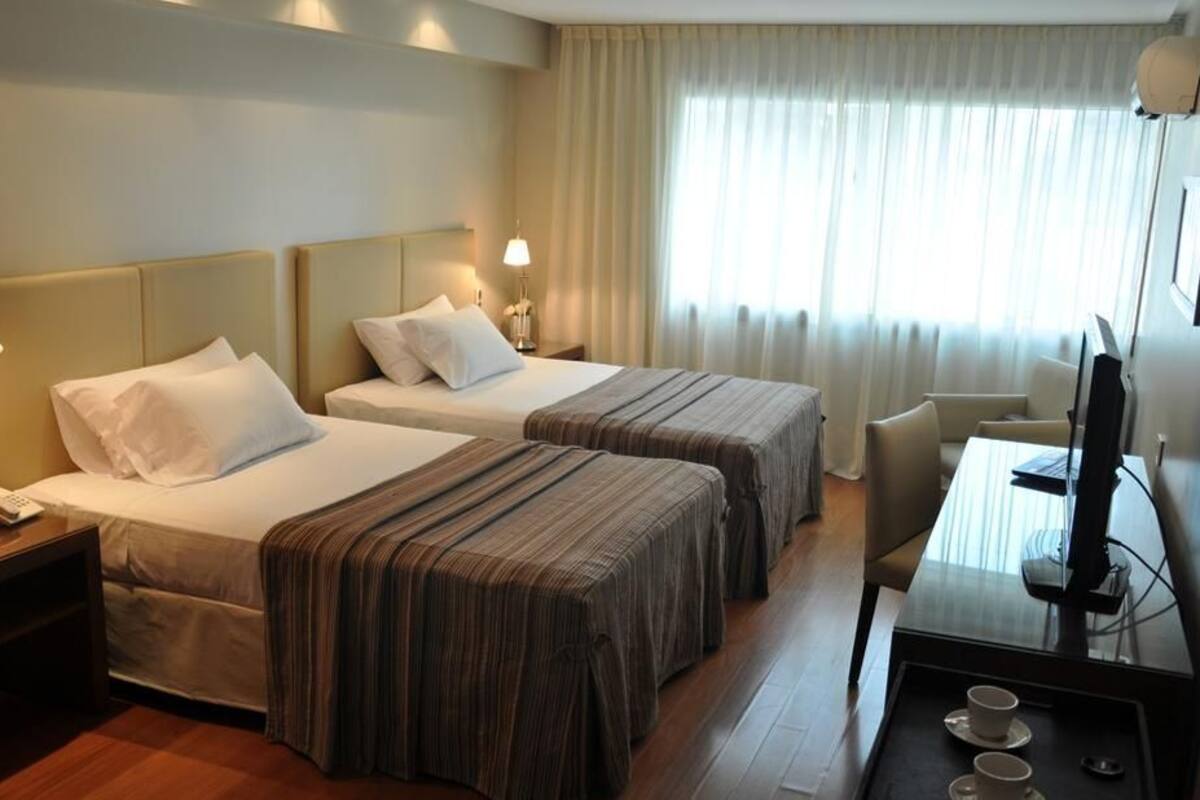 A hotel room with two beds, a desk with a computer, a TV, and a coffee maker.