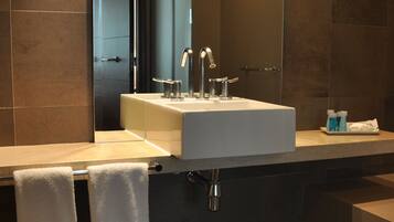 A modern bathroom with a white sink, two faucets, and a mirror.
