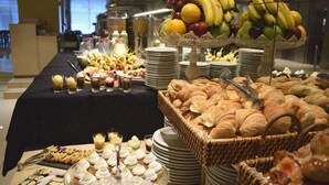Un buffet proposant une variété de plats, notamment des fruits, des pâtisseries et des desserts.