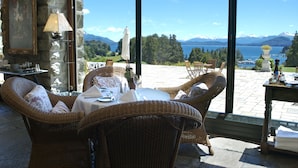 Un conjunto de comedor de mimbre con una mesa dispuesta para dos personas, con vistas a un lago y montañas panorámicos.